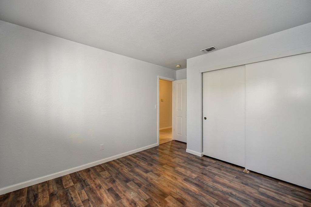Empty bedroom with dark wood-look flooring and a large sliding-door closet.