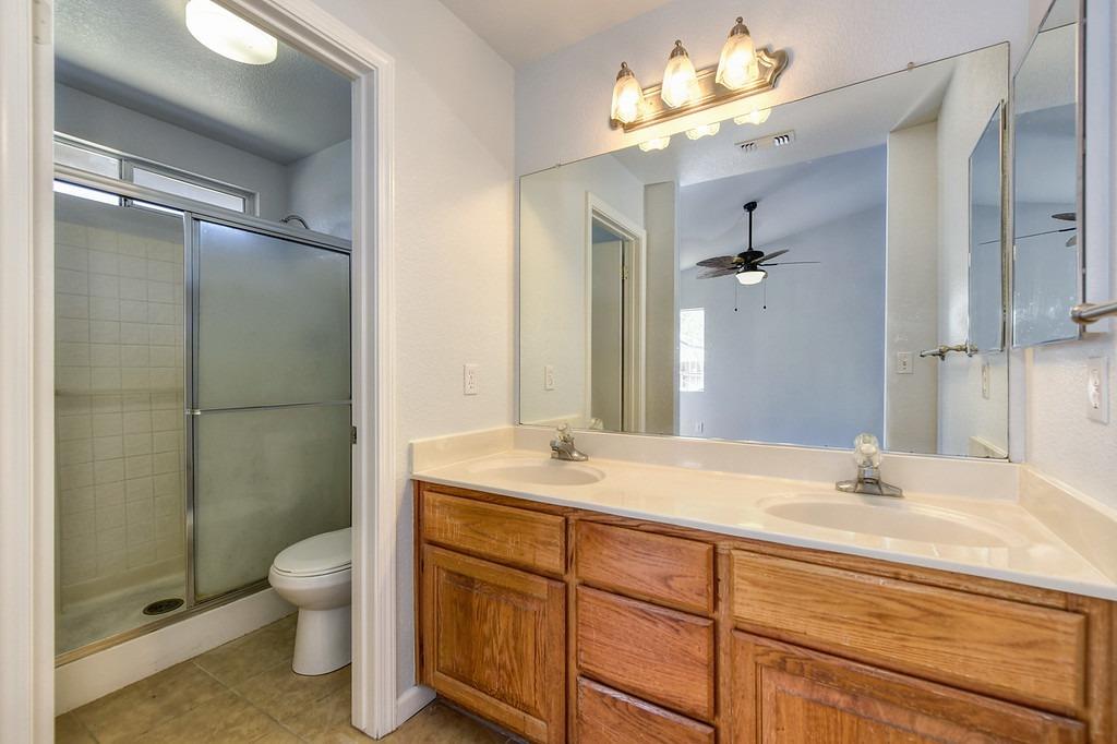 Bathroom with a double-sink wood vanity and an adjoining tiled shower.