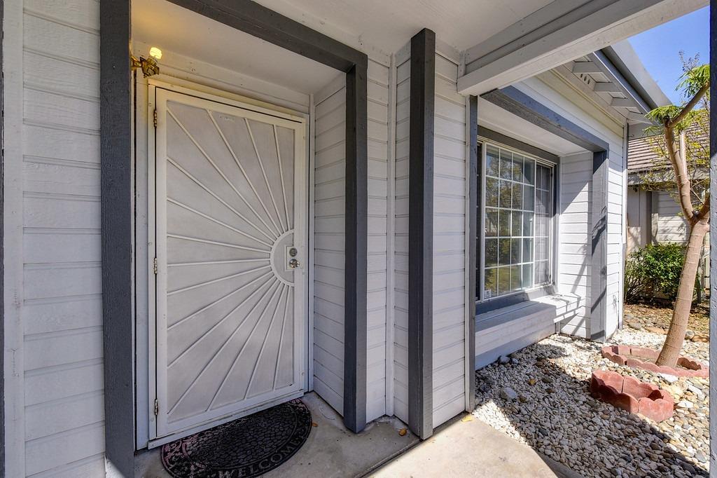 Home entrance with a sunburst-panel front door, dark trim, and a large divided-pane window.