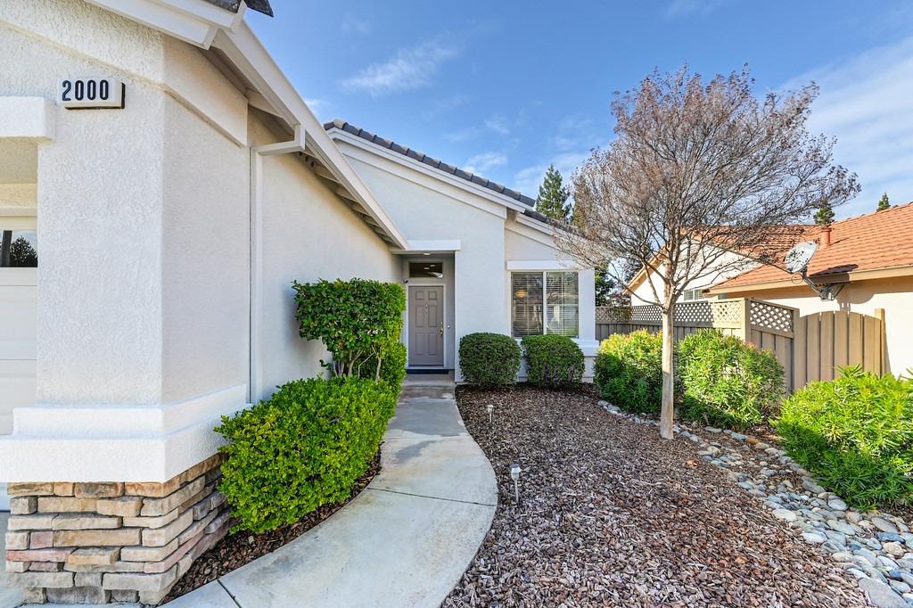 Home entrance with a curved walkway, landscaped shrubs, and the number 2000 beside the garage.