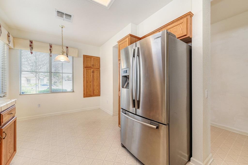 Kitchen with oak cabinets, a stainless steel refrigerator, and a window with blinds.