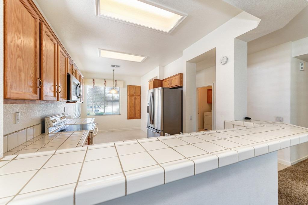 Kitchen with wood cabinets, stainless steel appliances, and a broad white tiled peninsula.