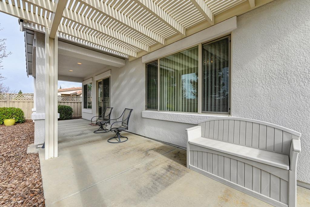 Covered patio with a white pergola, built-in bench, and two swivel chairs.