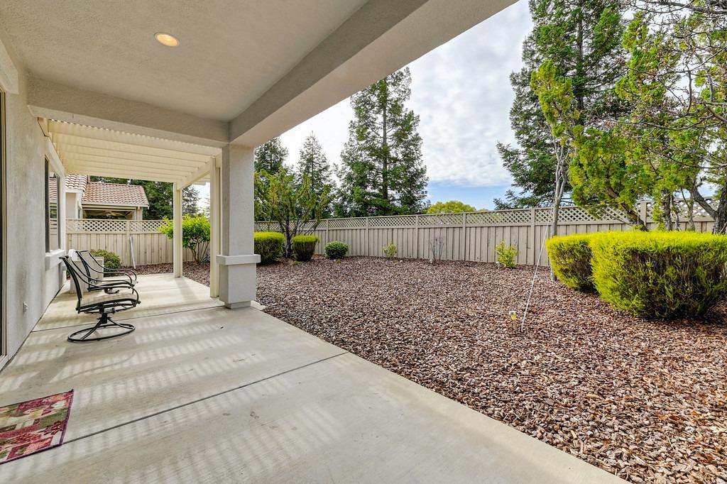 Covered patio with rocking chairs overlooking a fenced, mulch-covered backyard.