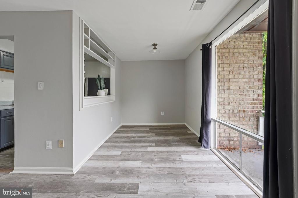 Unfurnished living area with gray plank flooring, a kitchen pass-through, and a large sliding glass door.