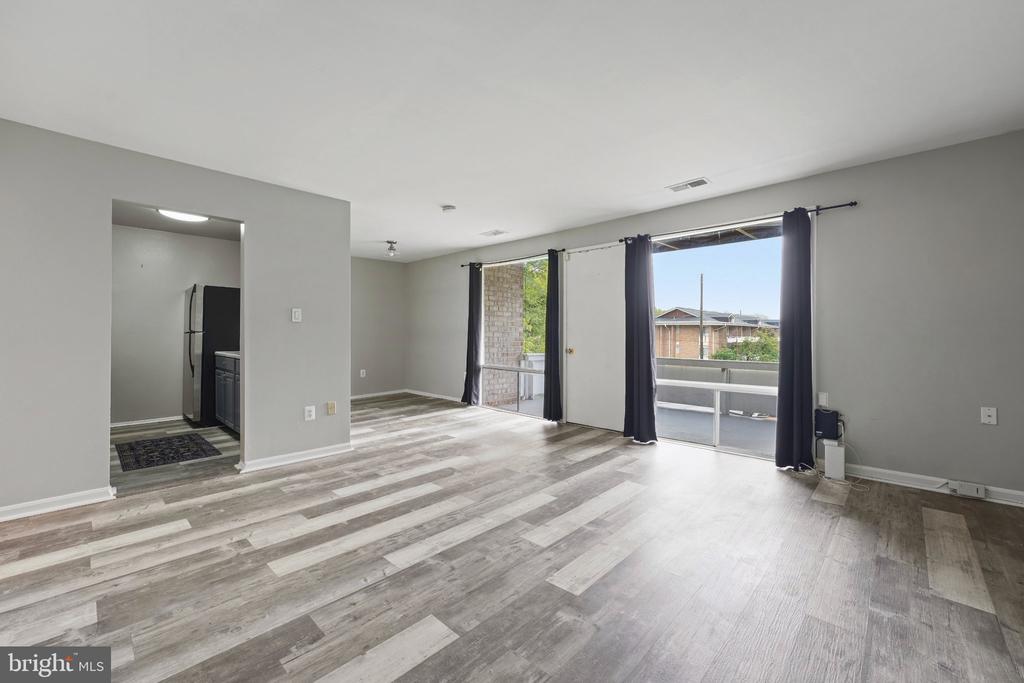 Vacant living area with gray plank flooring and sliding glass doors opening onto a balcony.