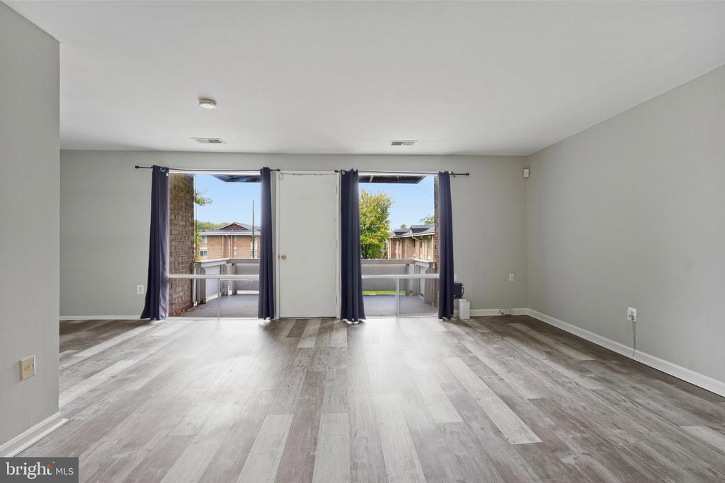 Vacant living room with gray plank flooring and sliding glass doors opening to a patio.