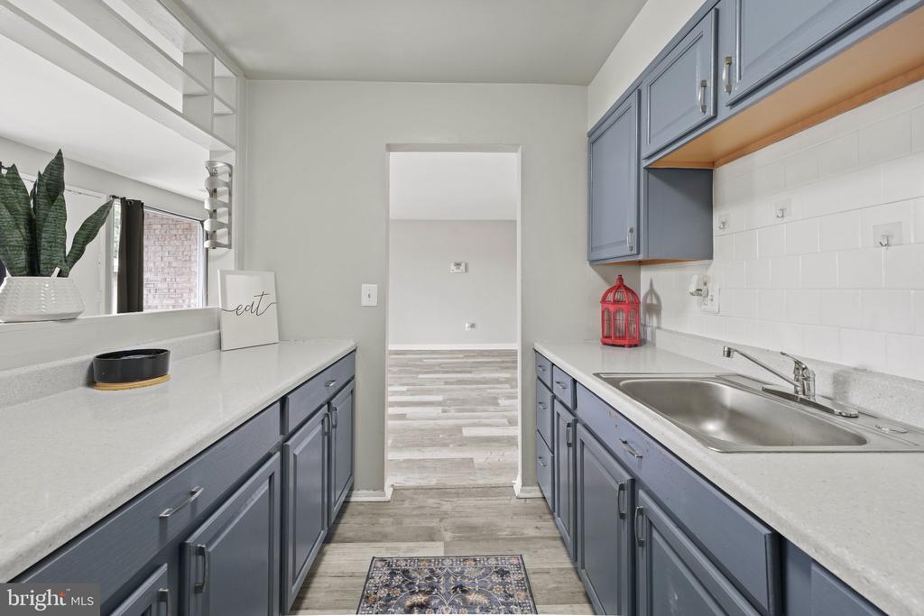 Kitchen with blue-gray cabinets, white counters, and a stainless-steel sink.