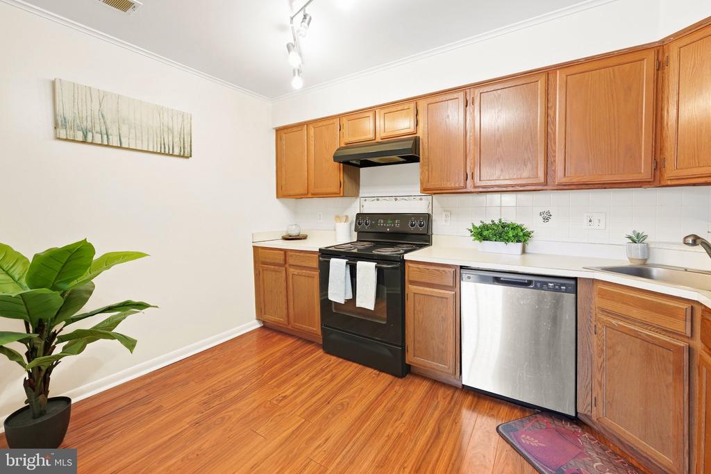 Kitchen with wood cabinets, hardwood floors, and a stainless-steel dishwasher.