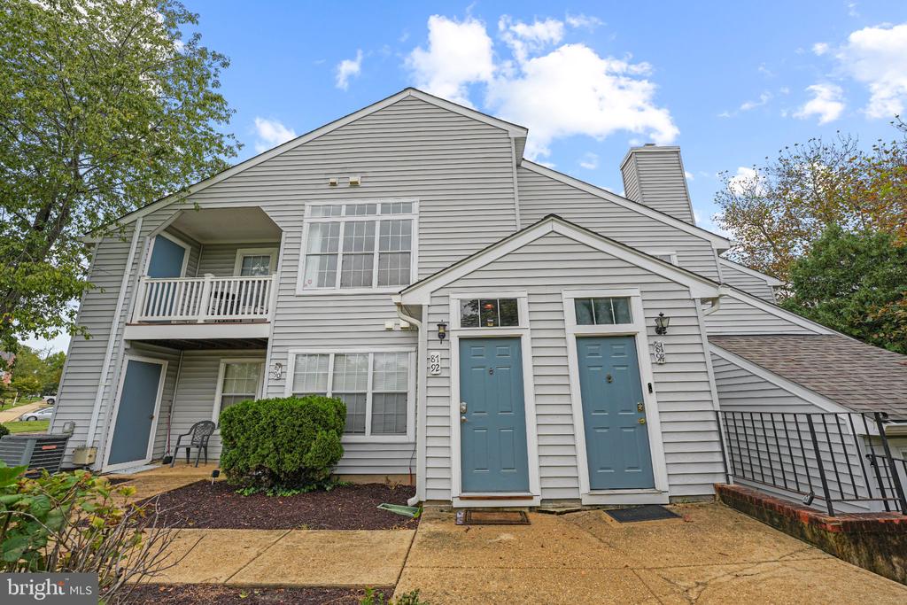 Gray-sided residence with two blue entry doors and a second-floor balcony.