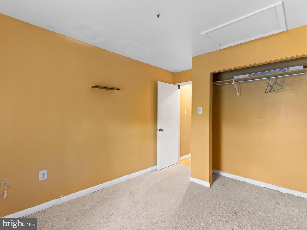 Empty bedroom with mustard-yellow walls, beige carpet, and an open closet.