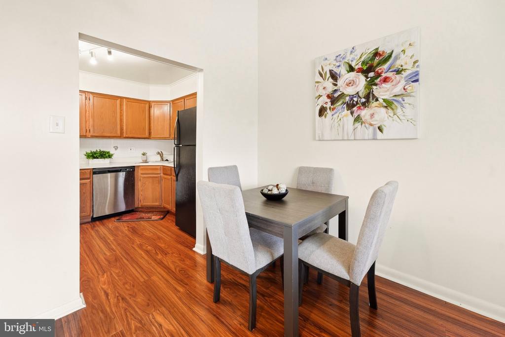 Dining area with a gray table and upholstered chairs beside a warm wood kitchen.