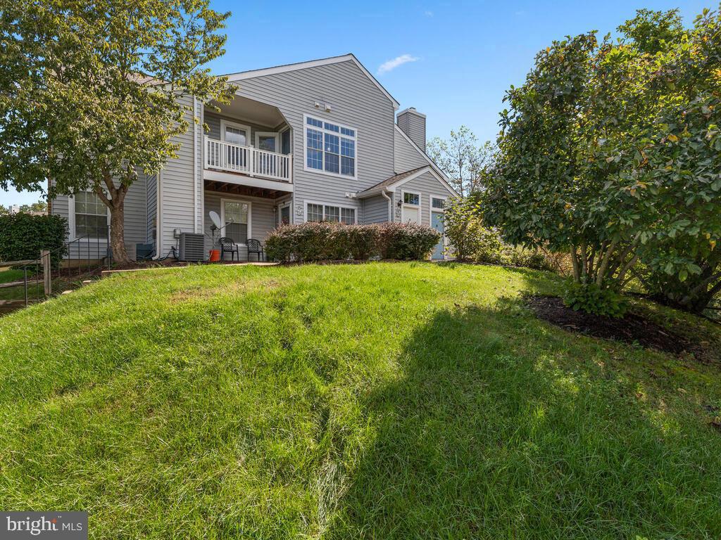 Gray two-story house with a raised deck and covered patio overlooking a sloped lawn.