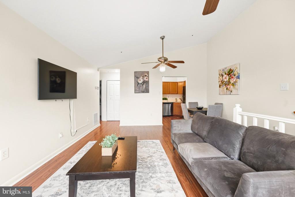 Living room with a gray sectional, dark wood coffee table, and kitchen visible beyond.