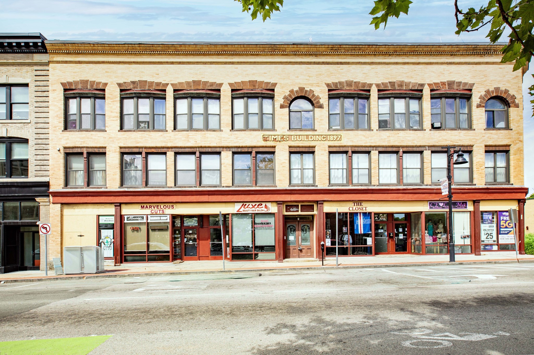 Three-story brick Times Building with arched upper windows and a row of ground-floor storefronts.