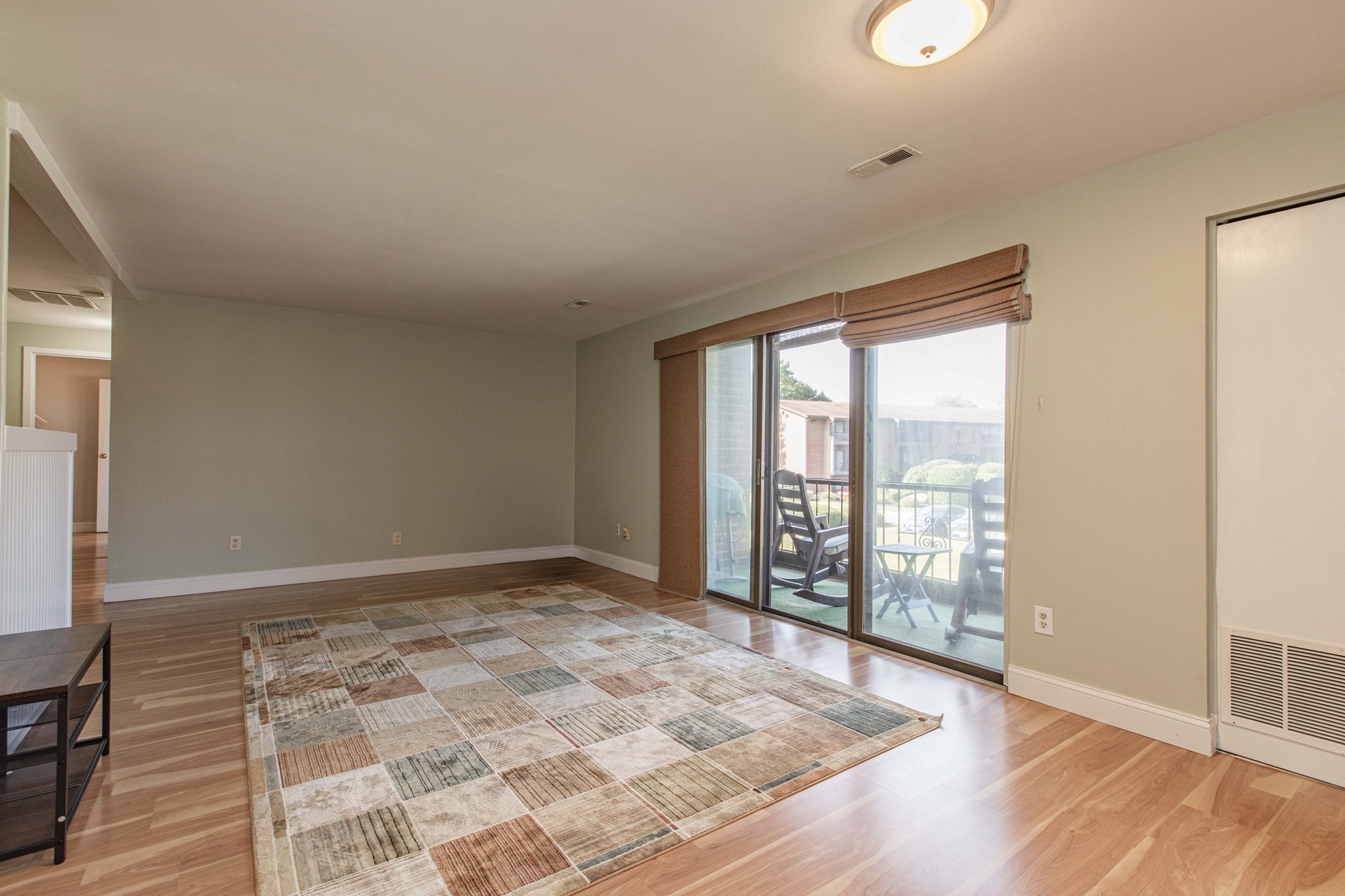 Living room with a large patterned rug and sliding glass doors opening onto a balcony.