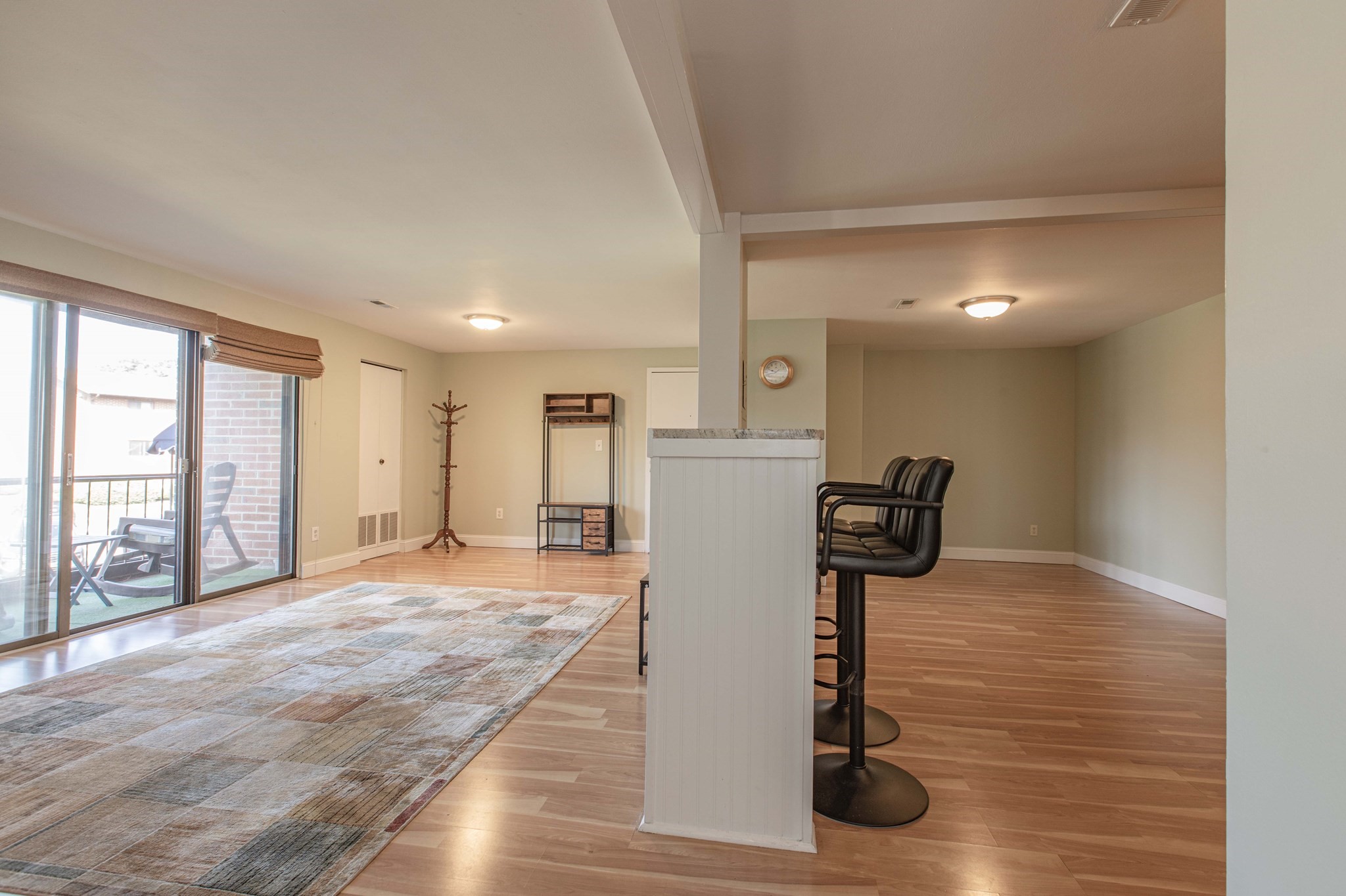 Open-plan living and dining area with a breakfast bar, wood floors, and sliding doors to a balcony.