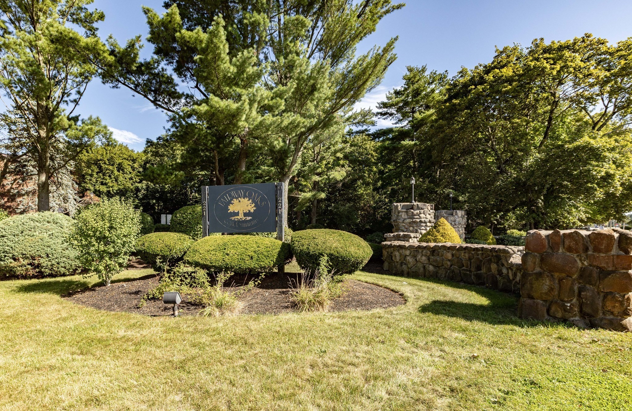 Willow Oaks community entrance sign amid landscaped grounds and a stone wall.