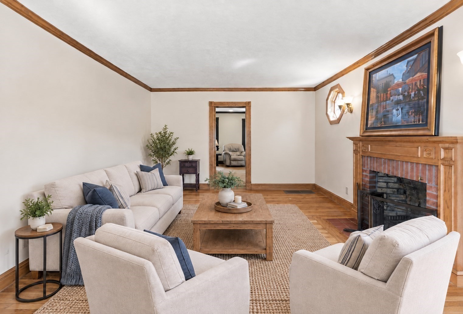 Staged living room with a wood-trimmed brick fireplace and light sofas around a coffee table.