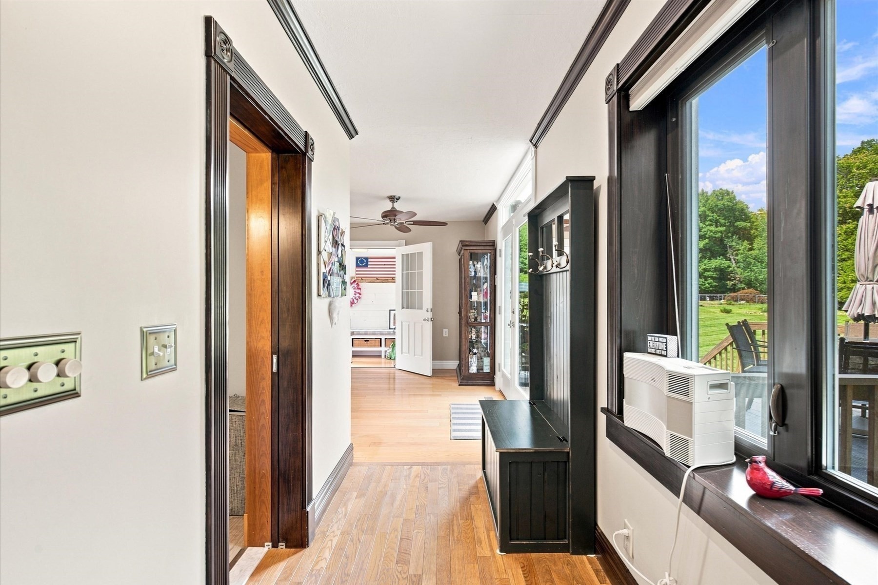 Sunroom with hardwood floors, tall windows, and a built-in bench overlooking a green lawn.