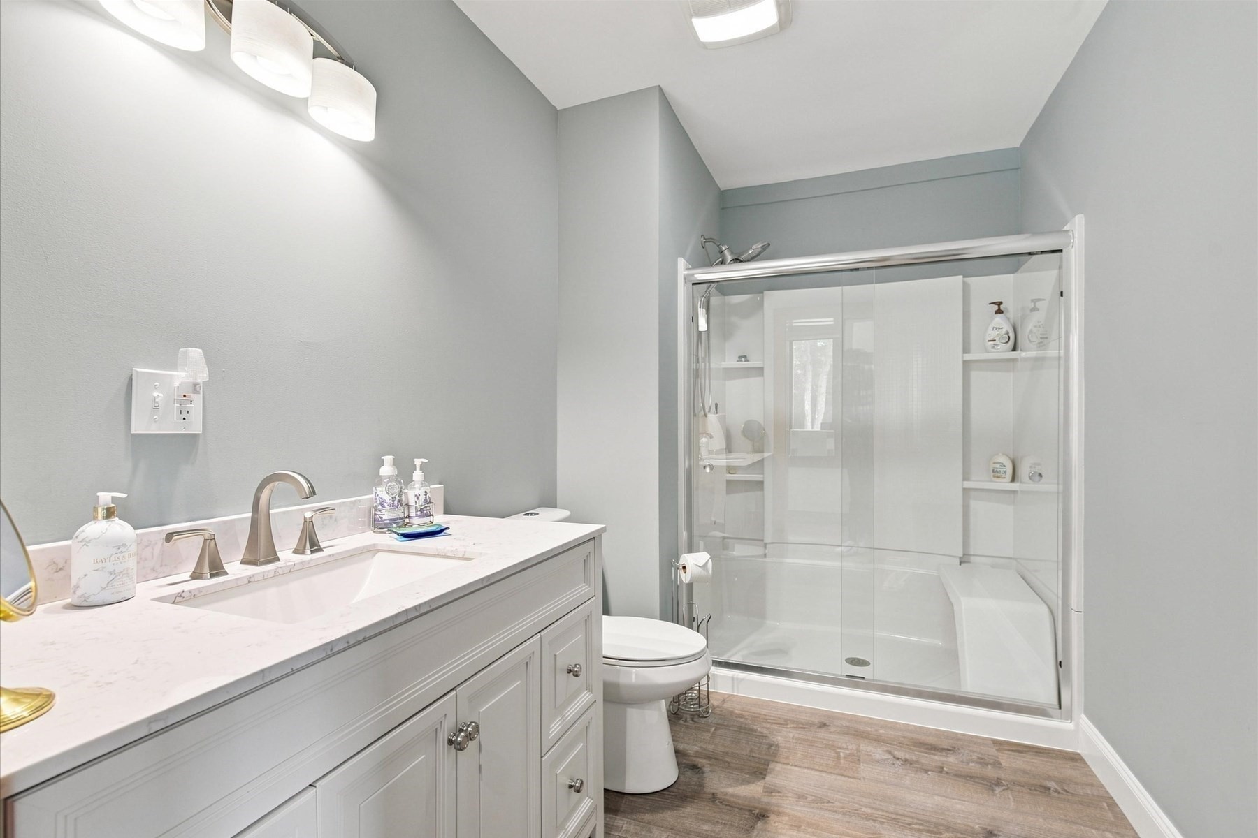 Bathroom with a white vanity and spacious glass-enclosed shower with built-in shelves.