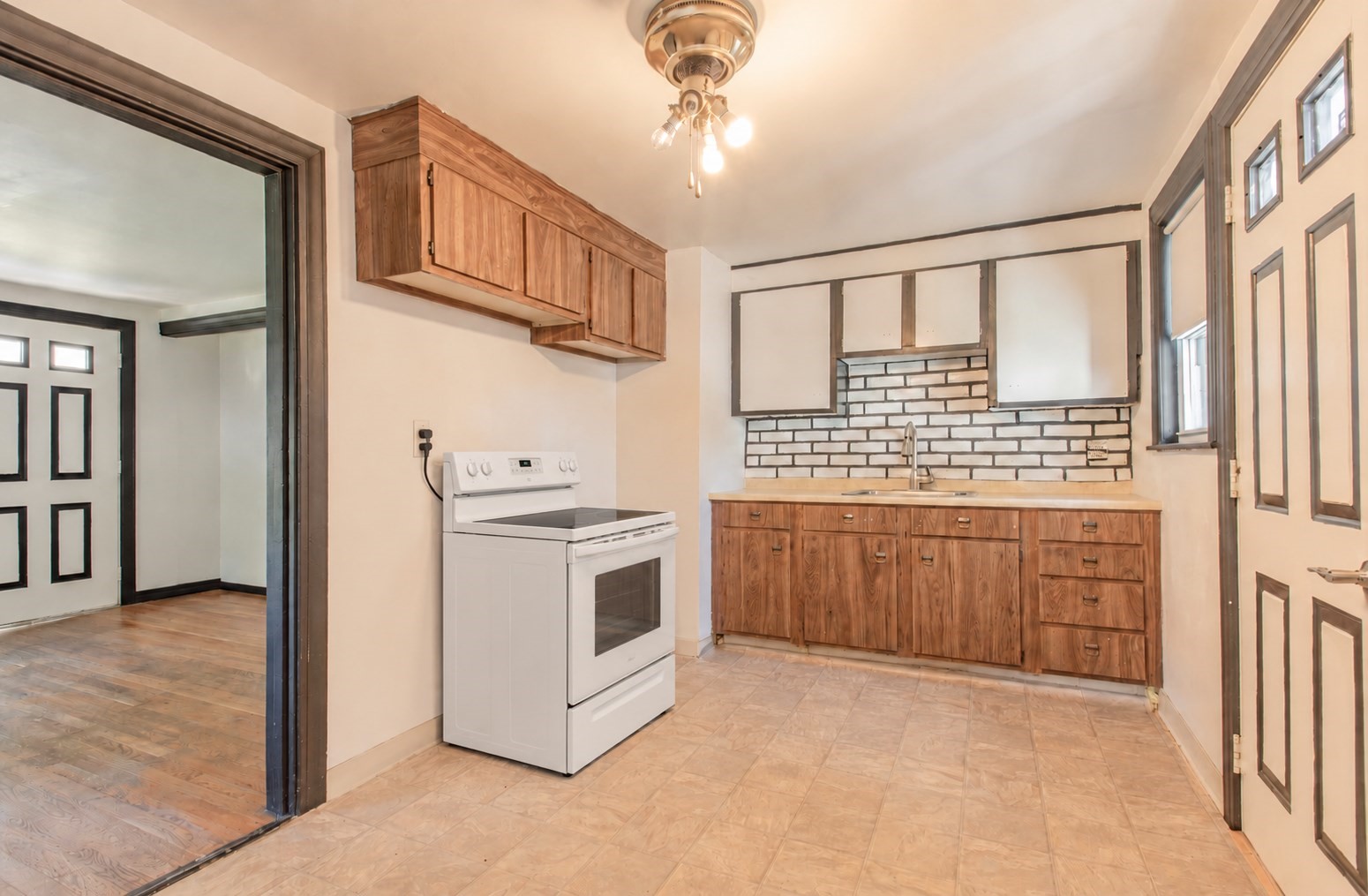 Kitchen with wood cabinets, white electric range, and dark-framed brick-pattern backsplash.