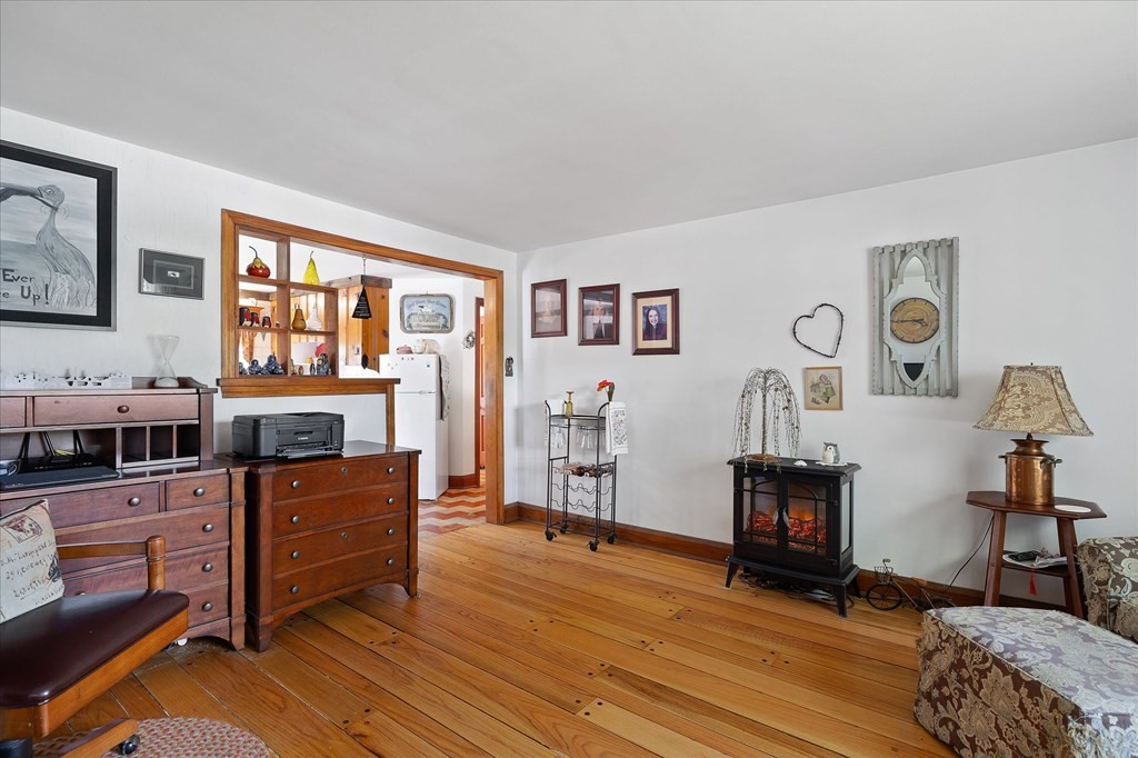 Living room with polished hardwood floors, dark wood furniture, and a freestanding stove.