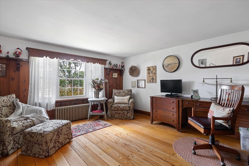 Furnished living room with patterned seating, dark wood furnishings, and honey-toned hardwood floors.
