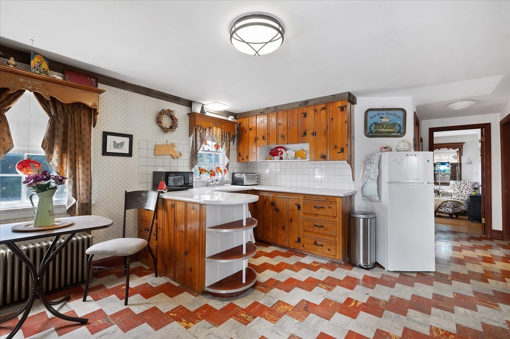 Kitchen with warm wood cabinets, a peninsula, and a bold red, white, and gray patterned floor.