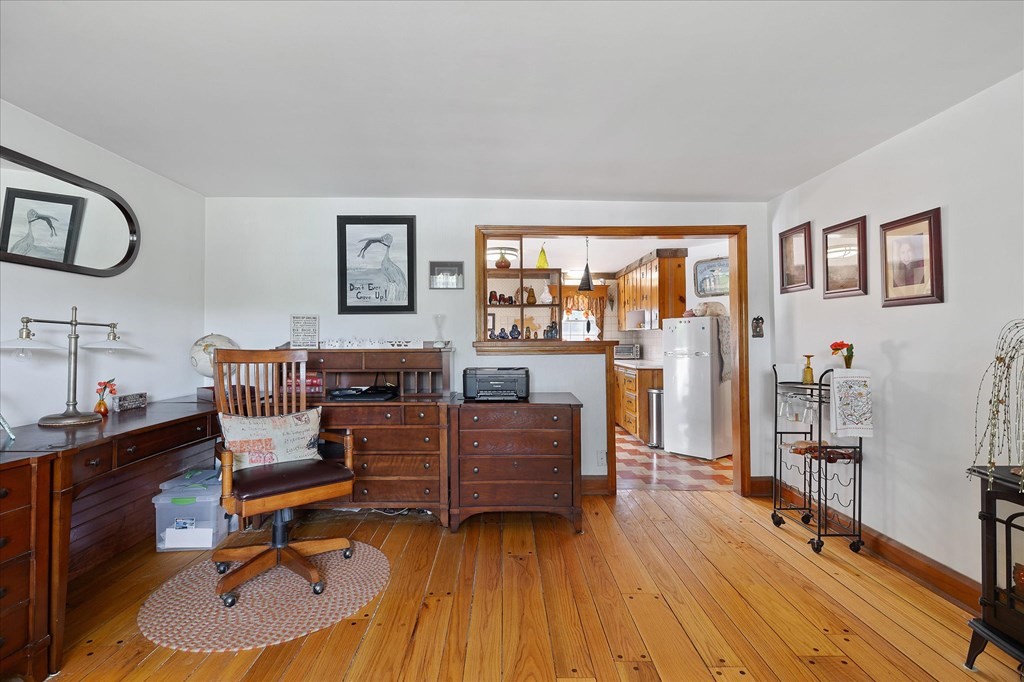 Furnished home office with antique wooden furniture and a wide opening into the kitchen.