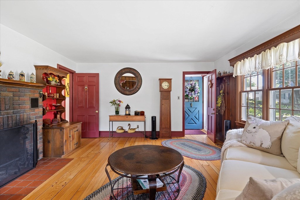 Living room with a brick fireplace, hardwood floors, and a blue front door.