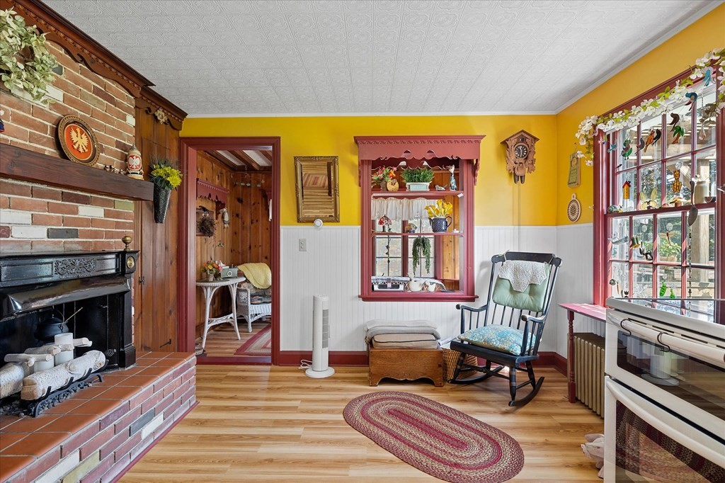 Sitting room with a brick fireplace, yellow walls, and a rocking chair by the windows.