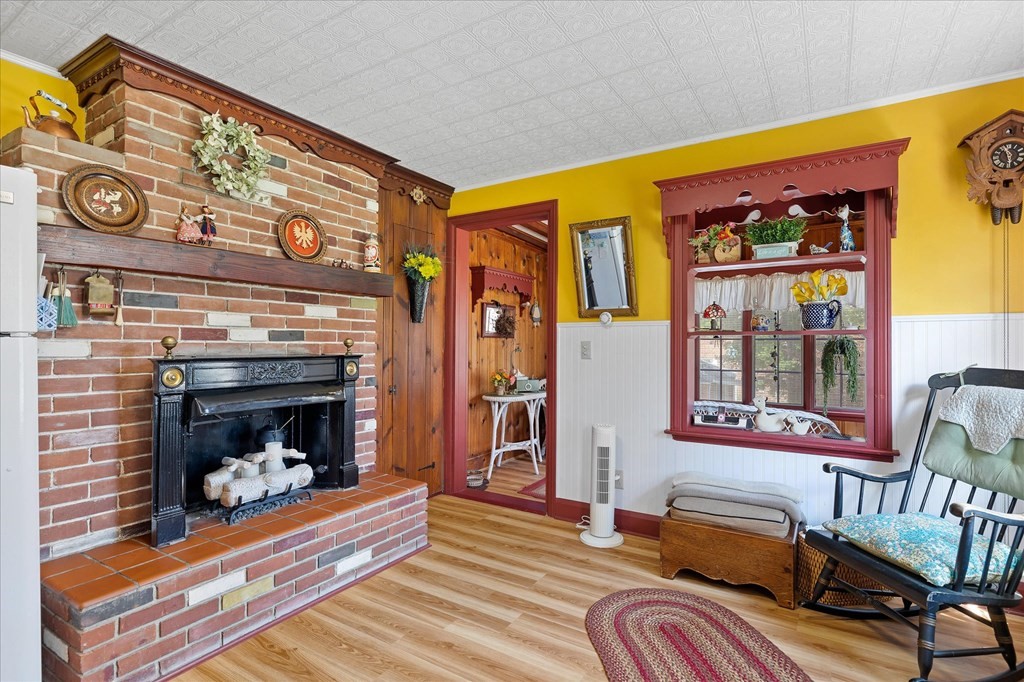 Living room with a brick fireplace, yellow walls, and dark red wood trim.