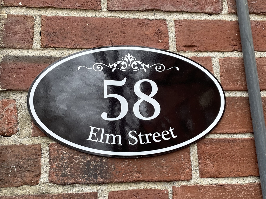 58 Elm Street address plaque mounted on a red brick wall.