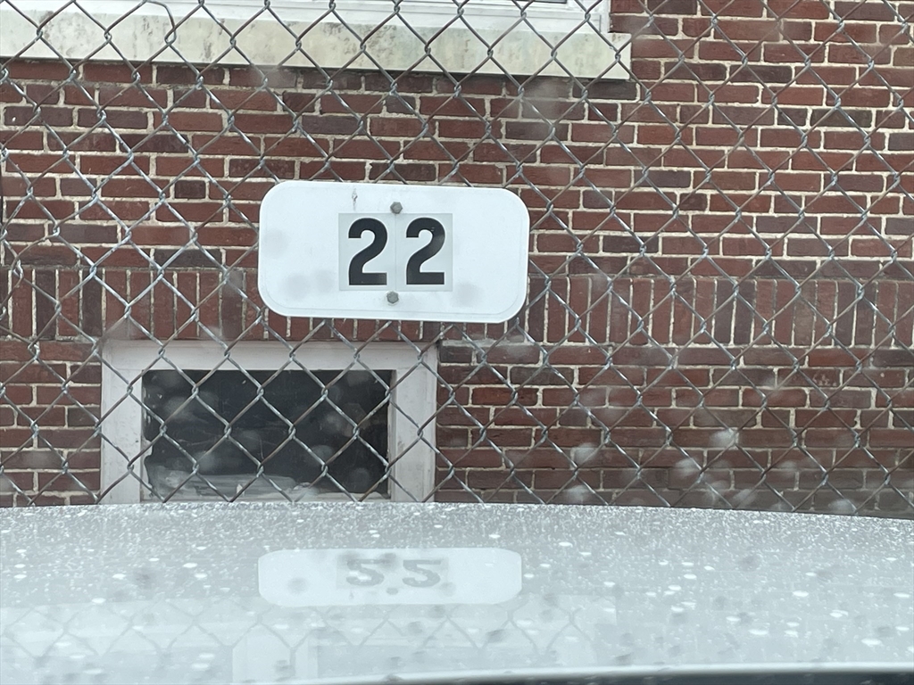 Brick exterior behind a chain-link fence, with a white sign marked 22.