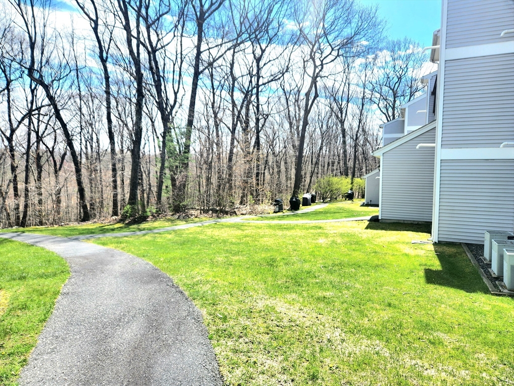 Residential buildings beside a curved walkway and green lawn, with leafless trees in the background.