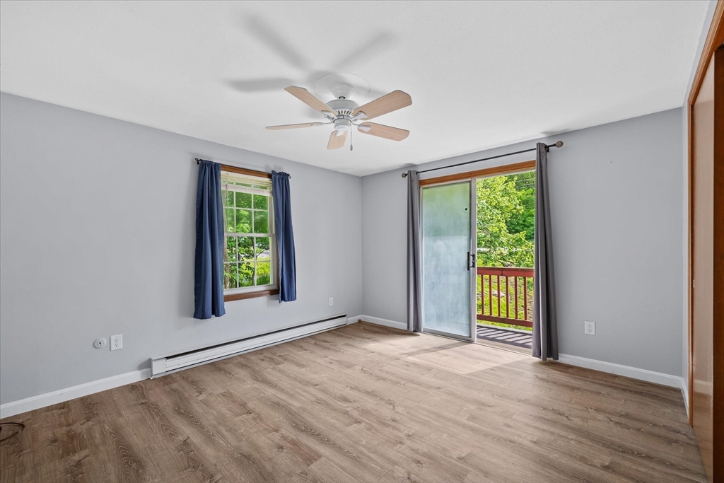 Empty room with wood-look flooring, a ceiling fan, and a sliding glass door opening to a balcony.