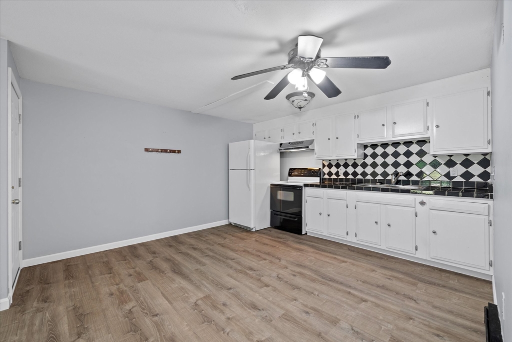 Kitchen with white cabinets, diamond-pattern backsplash, and wood-look flooring.