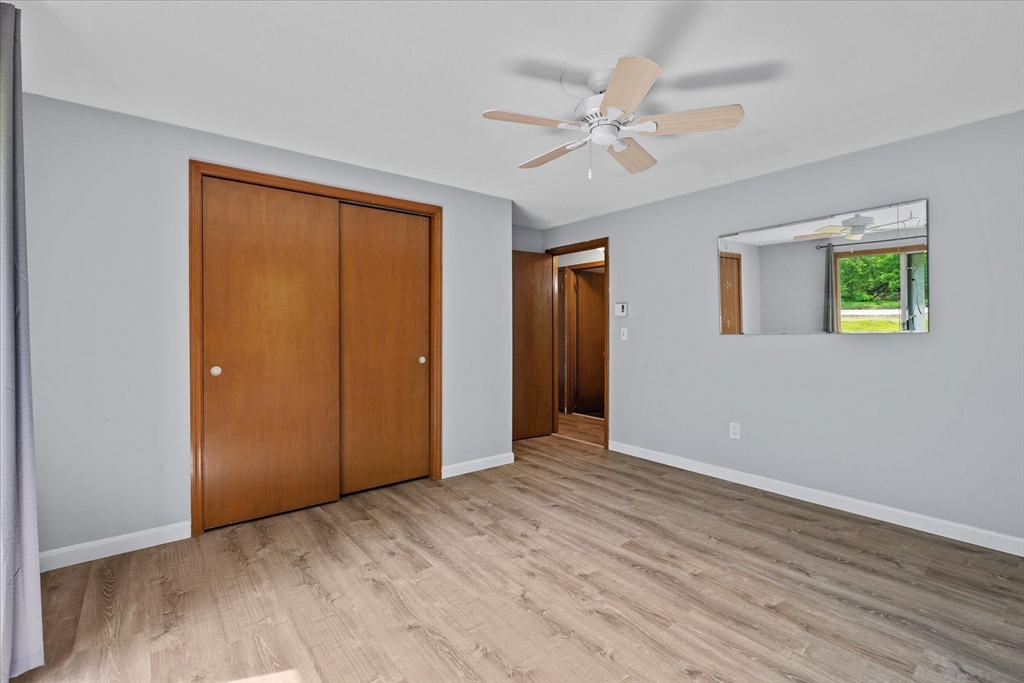 Empty bedroom with a wooden sliding-door closet, ceiling fan, and light wood-look flooring.