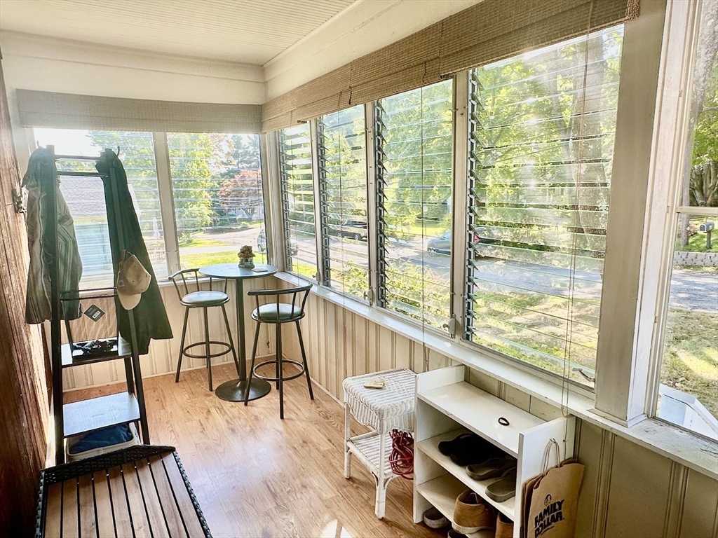Enclosed sunroom with jalousie windows, a small café table, and shoe storage.