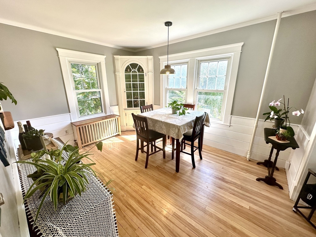 Dining room with hardwood floors, a table, and three tall windows.