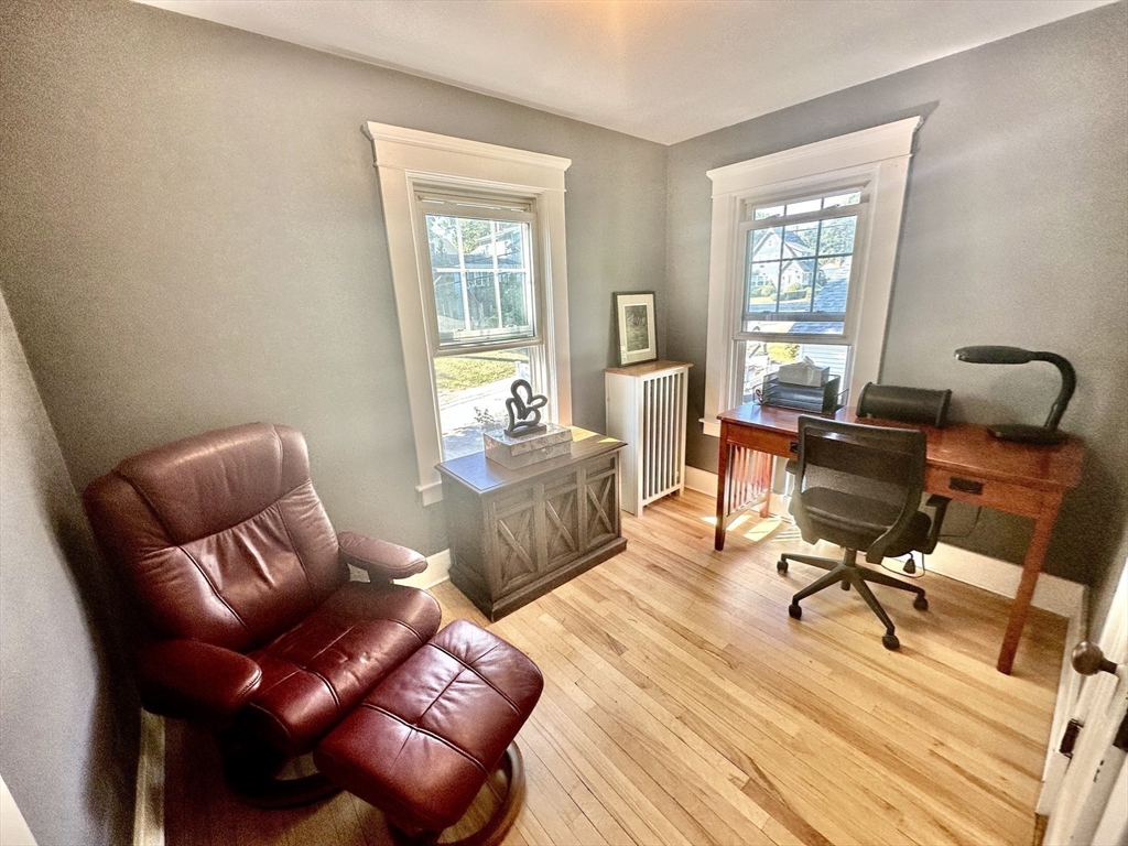 Home office with hardwood floors, a wooden desk, and burgundy leather recliner.