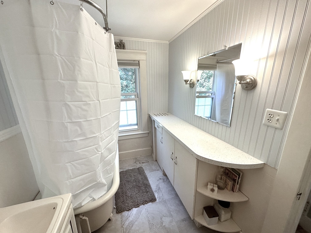 Bathroom with a long white vanity, large mirror, and tub behind a shower curtain.