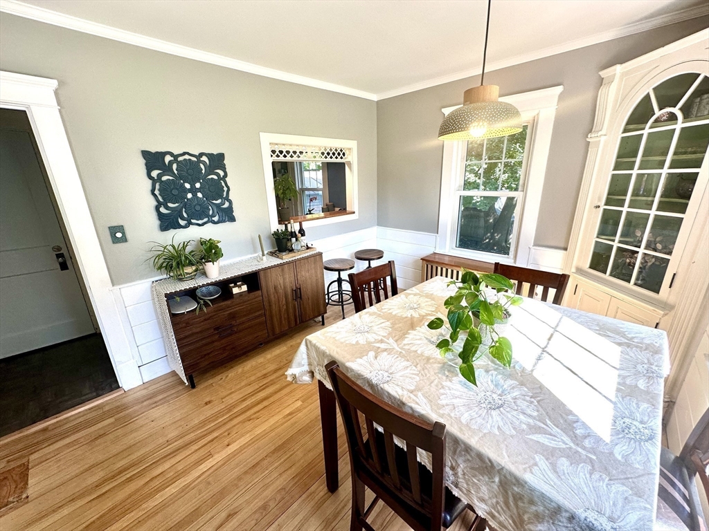 Dining room with a floral-covered table, hardwood floors, and a built-in glass-front cabinet.