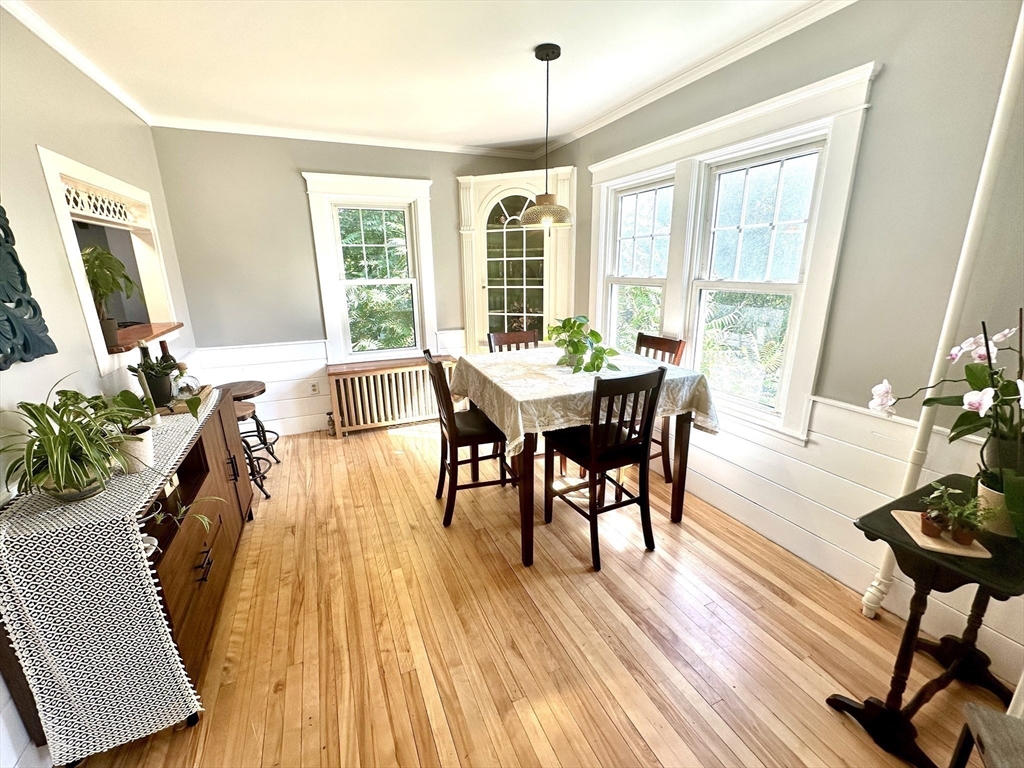 Dining room with a wooden table, polished hardwood floors, and large windows.