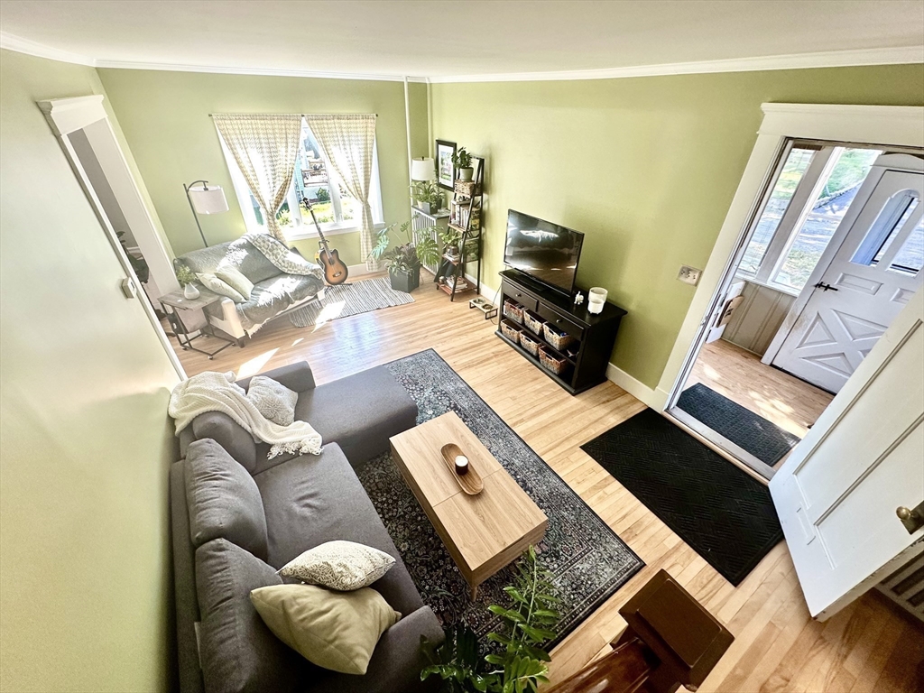Living room with pale green walls, gray seating, patterned rug, and light wood floors.