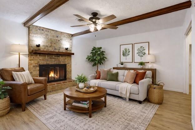 Living room with a stone fireplace, exposed wood ceiling beams, and a pale sofa.