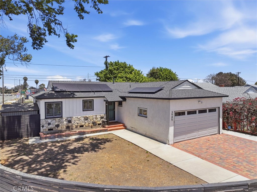 Single-story home with rooftop solar panels, stone facade, and attached garage.