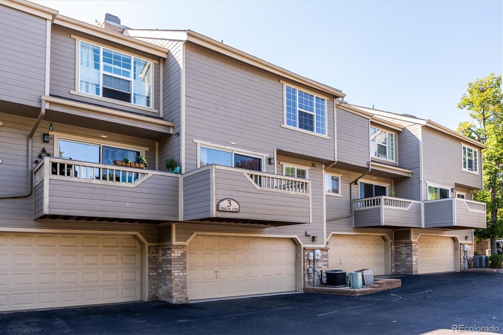 Gray townhomes with private balconies above attached garages.