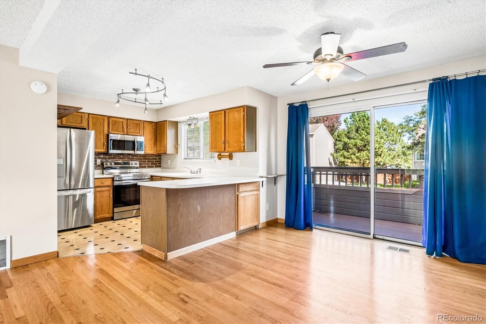 Open kitchen and dining area with wood cabinetry, stainless appliances, and sliding doors to a deck.